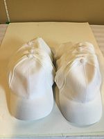 Front view of stacked white baseball caps