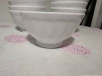 Side view of stacked white fluted bowls showing texture and footed base