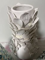 close view of white ceramic vase showing petal relief detail