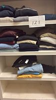 Stacked folded sweaters on upper shelf showing variety of colors and knits