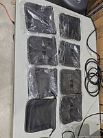 Eight pouches on table, seven in plastic packaging, one unpackaged showing front