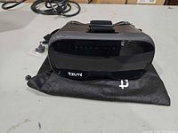Front view of Tzumi Dream Vision VR headset on pouch with spare parts bag