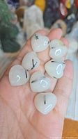 Eight small heart-shaped tourmalinated quartz stones in hand