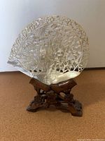 Full view of mother-of-pearl fan on wooden stand