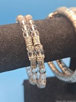 Close-up of two coil bracelets showing clear beads and silvertone spacers