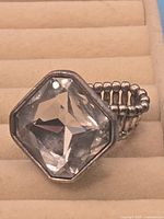 Front view of ring showing large clear faceted stone and bezel