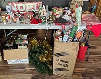 Full lot view on and under table: wrapping paper, ornaments, garland, figurines