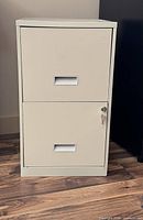 Full view of beige two-drawer metal filing cabinet with key in lock