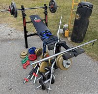 Group shot of bench, bars, plates, dumbbells, heavy bag