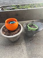 All four items grouped: large gray planter, orange pot inside, green pot, galvanized bucket