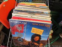 Photo showing a stack of LP vinyl records with Robert Plant 'Now and Zen' album prominently displayed in front. Records are in sleeves with varying condition, some sleeves show wear.