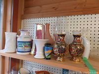 Shelf of various decorative vases showing shape, color, and style variety