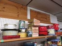 Shelf displaying vintage tins, mainly King Edward Imperial cigarette boxes stacked with various other decorative tins and one metal tray.