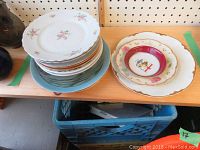 Stack of assorted plates showing various decorative styles and colors, including floral and holiday themes.