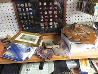 Overview of the shelf showing framed collector pins, framed prints, wood and metal wall decor, and coffee pot warmer.