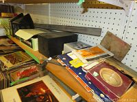 Shelf view showing boxed items, books, manuals, and a metal tray