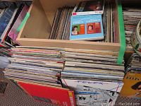 Photo showing stacks of LP records and a box of vinyls including a visible opera record featuring Tosca and Carmen highlights by Maria Callas and others.