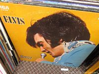 Close-up of Elvis Presley album cover with Elvis singing into microphone in blue outfit.