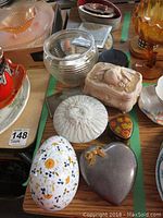 Overview of assorted trinket boxes, ashtrays, coasters, and decorative glass items on a table