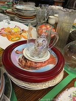 Photo showing glass mug with royal couple portrait and stack of collector plates underneath including red rim plate with Princess Diana image.