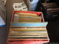 Box of LPs and 78 RPM records standing vertically showing edge of sleeves and some paper packaging.
