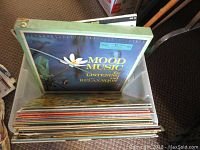 A bin of assorted LP vinyl records with visible wear, some with damaged or missing sleeves.