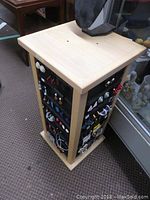 Rotating wooden jewelry stand showing black earring cards on all sides with various earrings.