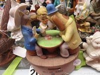 Side angle of ceramic music box showing two anthropomorphic dogs and child figure at table