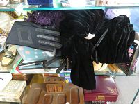 Top view of black leather gloves with black velvet vintage top and pouches underneath.