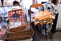 Photo showing the painted wooden vintage chair with seat pad and the kids wicker picnic set with checkered cloth basket and vintage covered wicker basket on a chair and table setup.