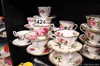 Full view of stacked vintage teacups and saucers with rose floral patterns and gold trim