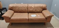 Front view of tan leather 2-seat sofa
