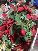 Pile of red silk poinsettia stems with green leaves