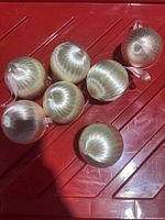 Seven blonde hair-covered ornaments grouped on red surface