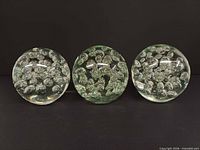 Front view of three clear glass paperweights showing controlled bubbles