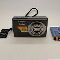 Front view of Kodak EasyShare M420 camera with lens retracted, battery and memory card shown