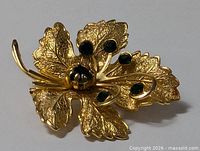 Front view of gold plated leaf brooch with green stones