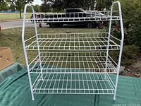 White metal wire three-tier shoe rack on outdoor table