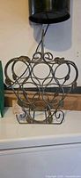 Full view of wrought iron wine rack front showing six circular bottle holders and leaf accents