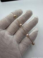 Bracelet draped across gloved hand showing pearl spacing and chain detail