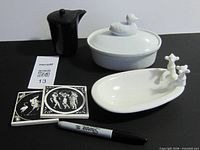 entire lot displayed: black creamer, white duck dish, giraffe tray, two tiles, pen for scale