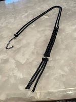 Full view of gunmetal lariat tassel necklace laid flat