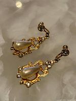 Both earrings showing front view with faux pearls, rhinestones and gold-tone filigree