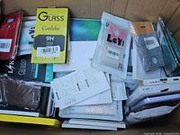 Box filled with packaged phone cases and glass protectors showing various brands and styles