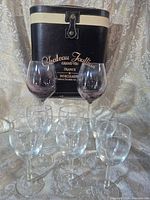 Eight wine glasses and Chateau Joullian case displayed on fabric backdrop