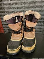 Front view of pair of winter boots showing materials, laces, faux fur lining and wear