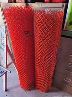 Two rolls orange plastic safety fence mesh standing vertically