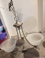 Full view of chandelier showing metal frame, three frosted glass shades, hanging chain