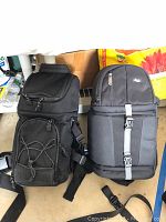 Two black camera sling bags side by side showing overall design, straps, and zipper compartments.