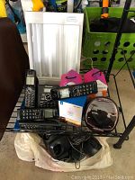 Overview of the lot on a table showing Panasonic cordless phone base with four handsets, smart plugs, Winter Sunshine light panel, and various power adapters.